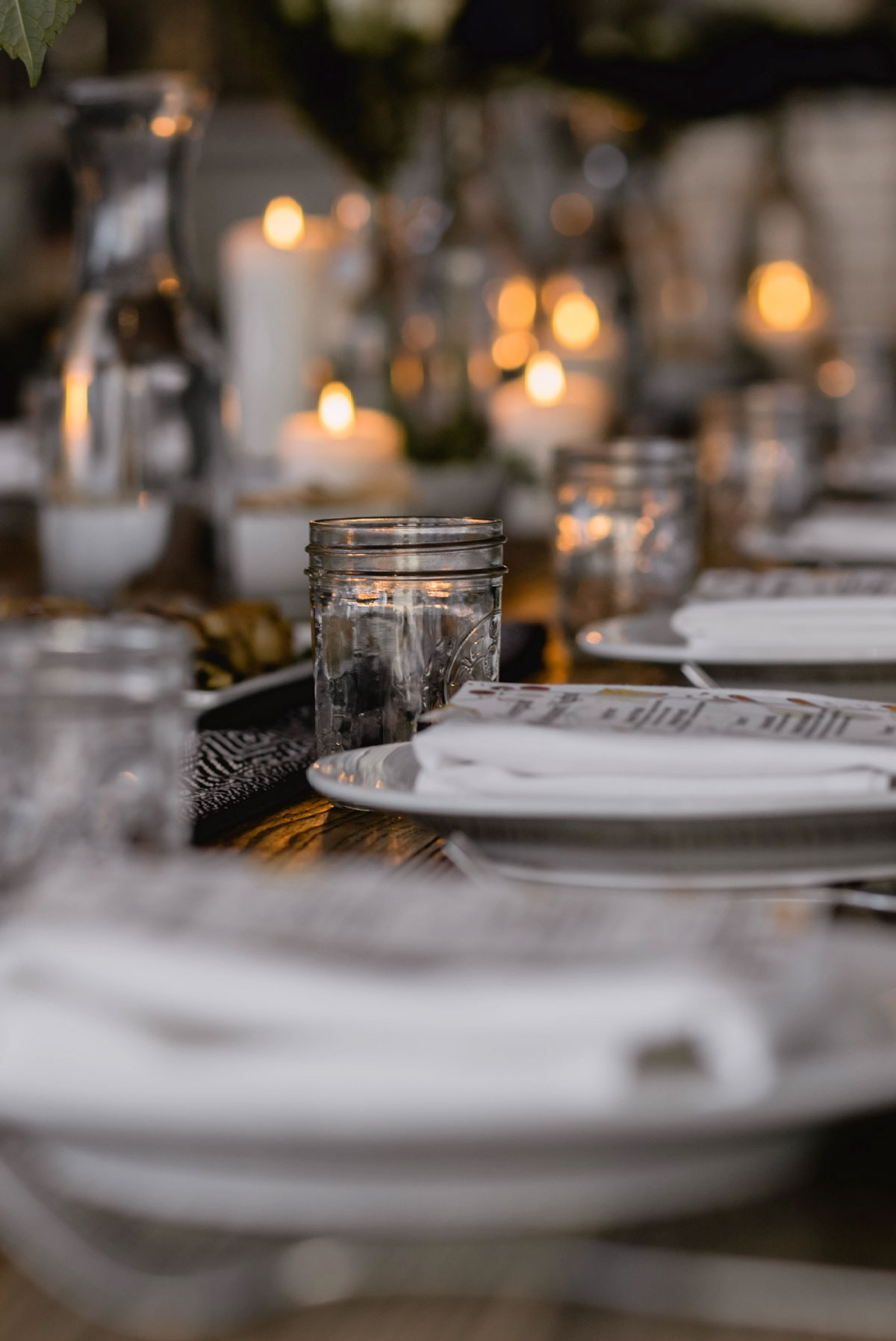Planning an event and ready to share Fresno's best Italian with your guests? We'll host your party on our gorgeous patio, or bring the party to you with a catering package! Pictured: a place setting at a long buffet table covered with crisp white linens. Candles glow in the background.
