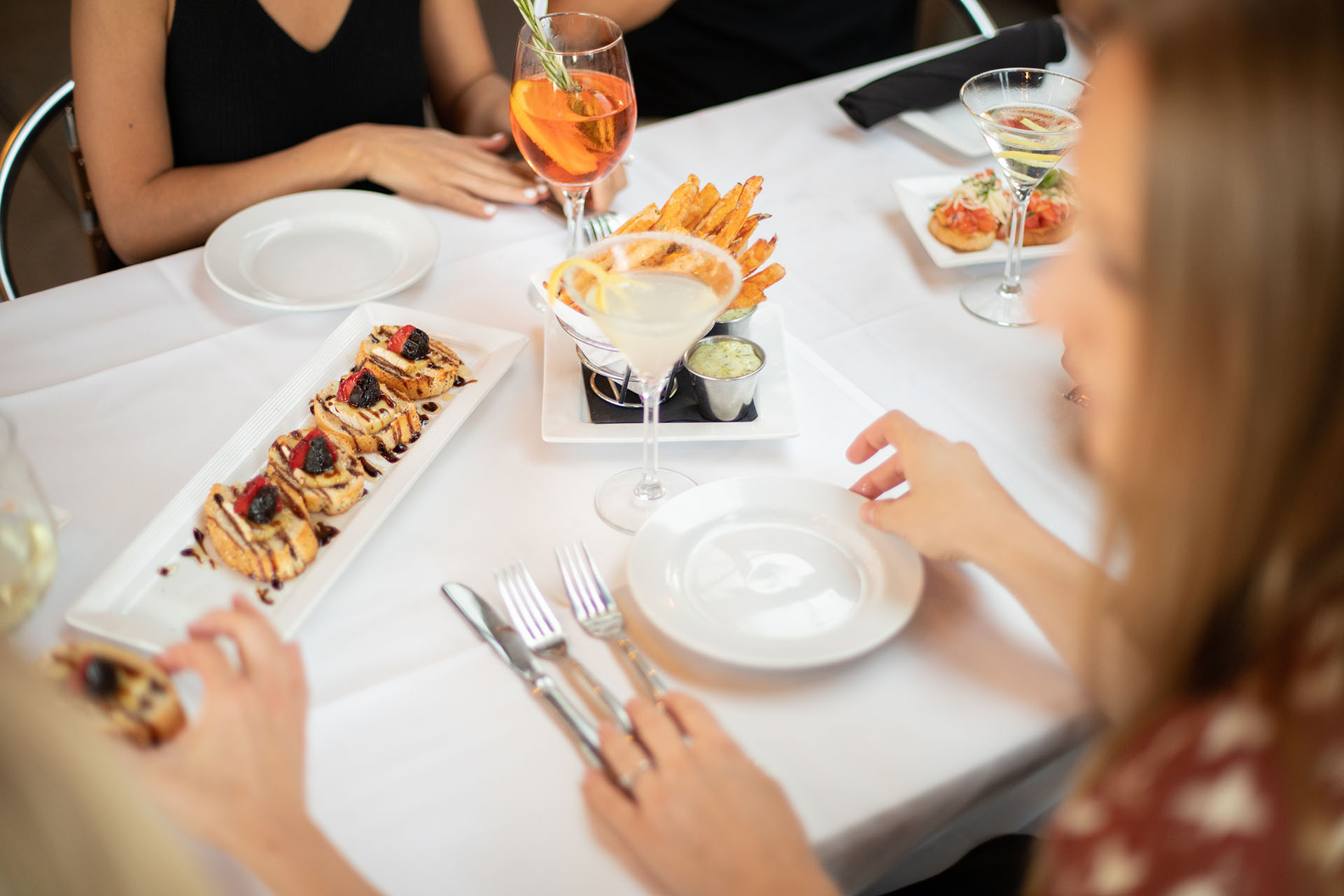 At Piazza del Pane, you'll find Fresno's best Italian dining. Our chef-curated menu is always farmers' market fresh. Pictured: our warm brie crostini appetizer with mission figs, strawberry, and balsamic glaze; house-made sweet potato fries with cilantro aioli; tomato bruschetta with fresh basil and roasted garlic; and two seasonal cocktails garnished with citrus and rosemary.